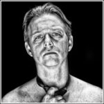 Zwart-wit portret van een man van middelbare leeftijd met een ernstige uitdrukking, dramatisch van boven belicht. Hij is shirtloos en heeft een losjes gestrikte stropdas op zijn borst, tegen een donkere achtergrond.